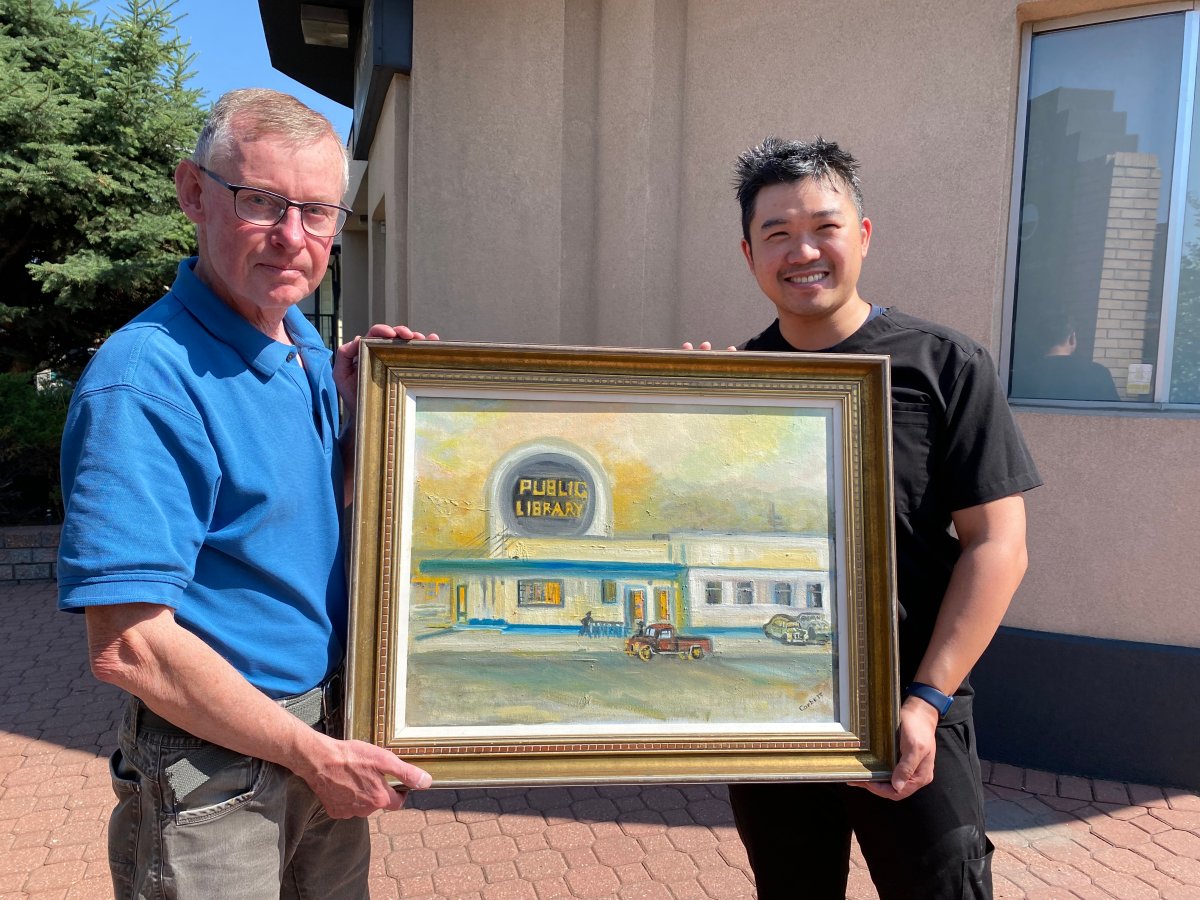 John McDermid (L) and Gilbert Ng hold the painting of the old Crescent Heights library on June 29, 2023.