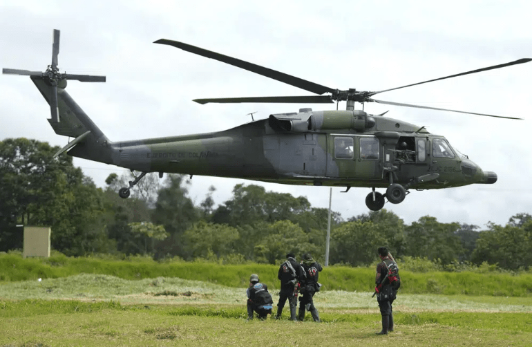 A helicopter taking off. There is a rope hanging.