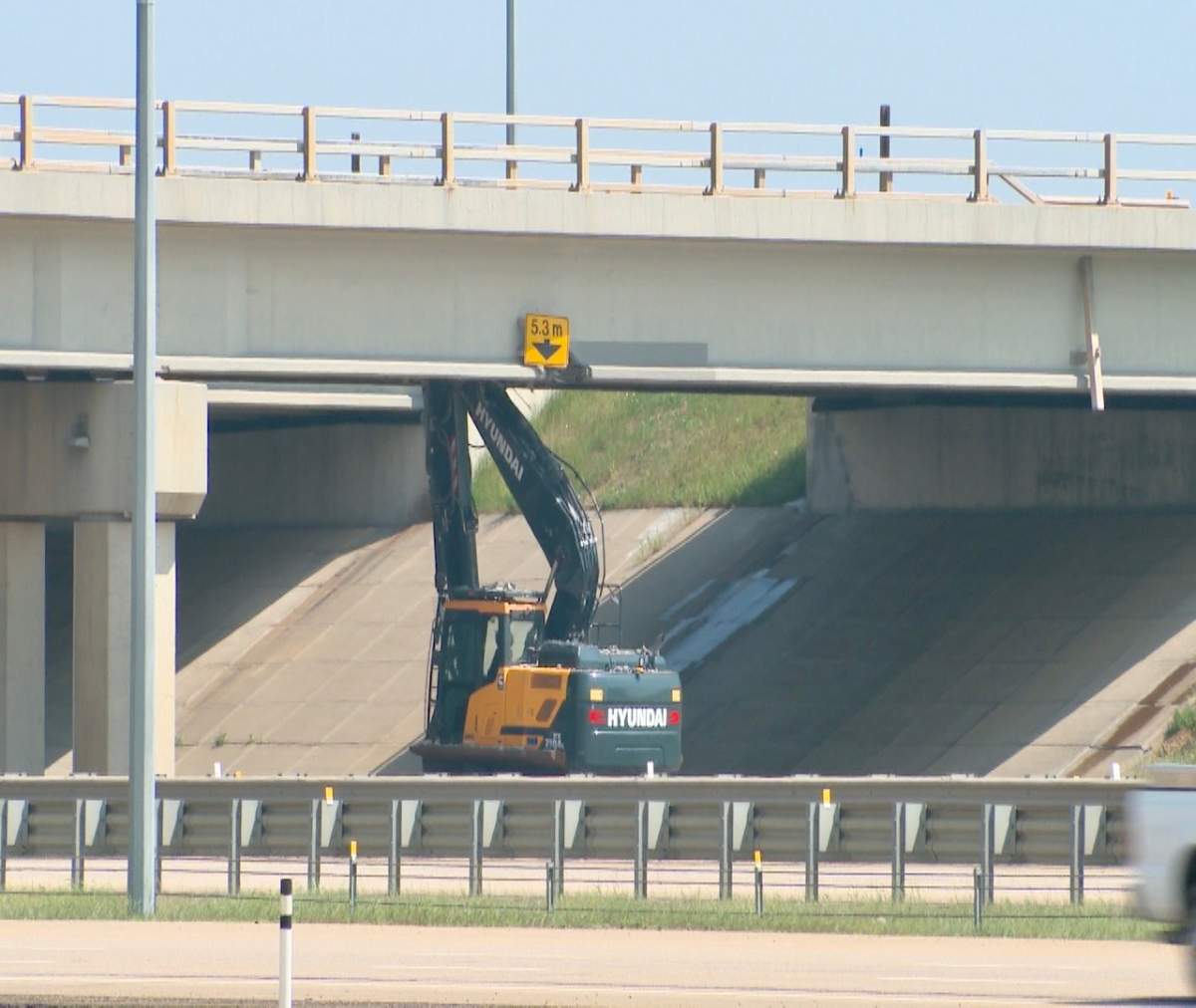 An excavator on a semi trailer collided with overpass bridge deck of Whitemud Drive at Anthony Henday Drive in southeast Edmonton on Friday, June 16, 2023.