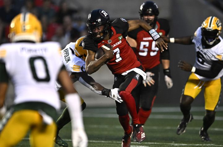 Ottawa Redblacks quarterback Tyrie Adams (7) tries to run past the tackle of Edmonton Elks linebacker Woodly Appolon (33) during first half CFL football action in Ottawa on Friday, June 30, 2023.