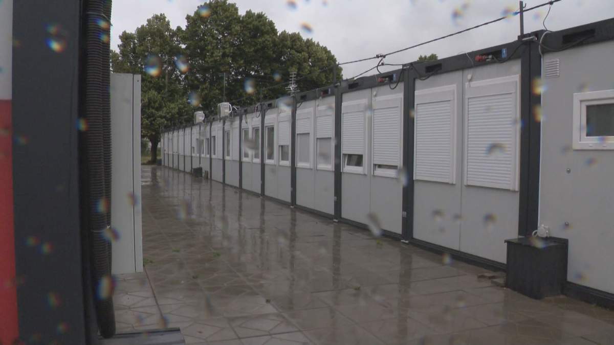 Rows of modular housing units stand against a grey, rainy sky.