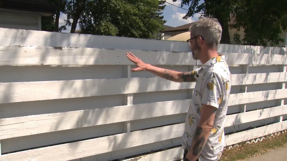 Jordan Barrett points to the portion of his fence that was vandalized with Nazi-themed symbols and phrases on June 4, 2023.