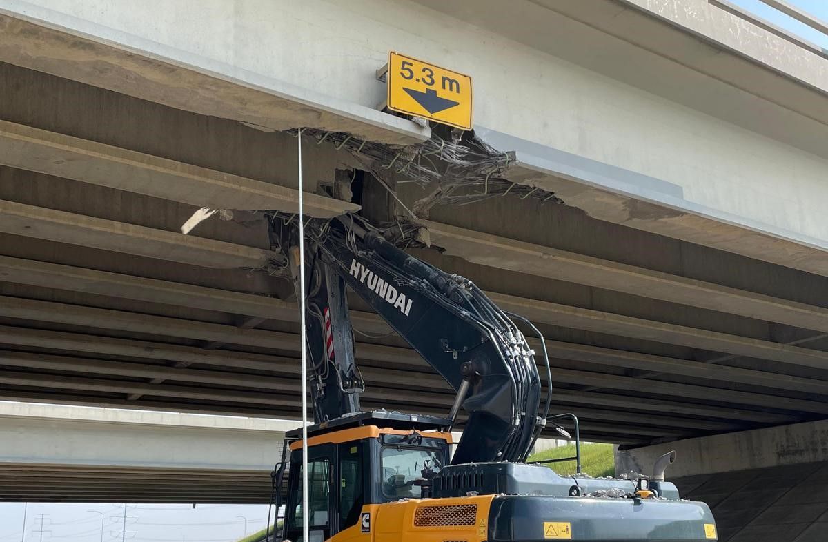 An excavator on a semi trailer collided with overpass bridge deck of Whitemud Drive at Anthony Henday Drive in southeast Edmonton on Friday, June 16, 2023.