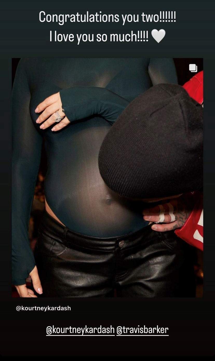 Kris Jenner's Instagram story. It is a photo of Travis Barker kissing Kourtney Kardashian's baby bump over her bodysuit.