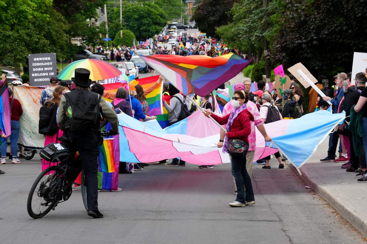 Counter protesters carry Pride and Trans Pride flags to confront a protest against Pride in Ottawa.