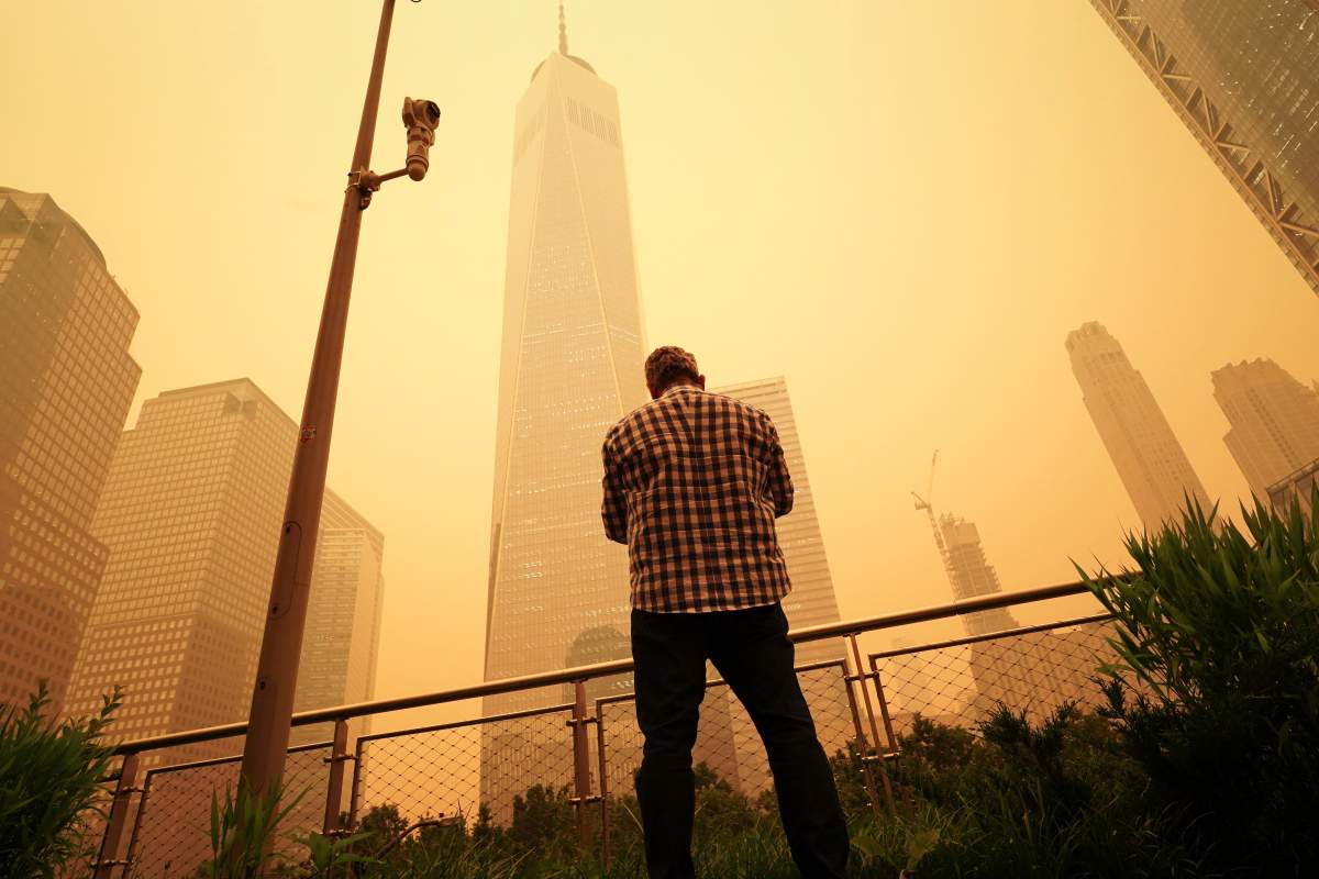 A man pauses to look at the smoke and haze shrouding One World Trade Center building in New York City, Wednesday, June 7, 2023. Intense Canadian wildfires are blanketing the northeastern U.S. in a haze, turning the air acrid and the sky yellowish gray. (AP Photo/J. David Ake)