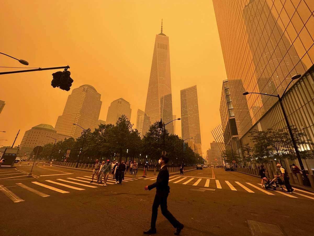 Pedestrians pass the One World Trade Center, center, amidst a smokey haze from wildfires in Canada, Wednesday, June 7, 2023, in New York. Smoke from Canadian wildfires poured into the U.S. East Coast and Midwest on Wednesday, covering the capitals of both nations in an unhealthy haze, holding up flights at major airports and prompting people to fish out pandemic-era face masks. (AP Photo/Julie Jacobson)