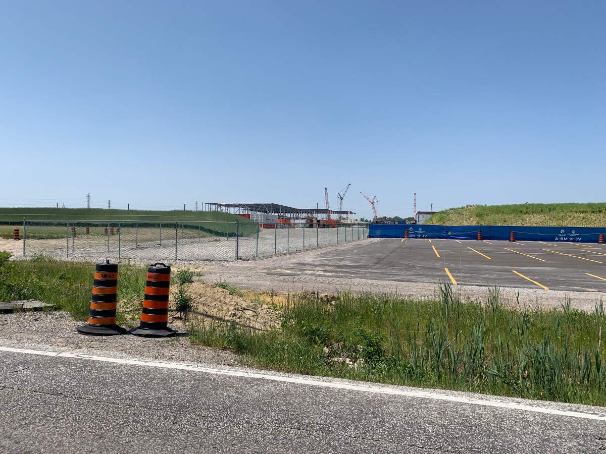 The frame of a large building and construction cranes can be seen in the background with pylons and a road in the foreground.