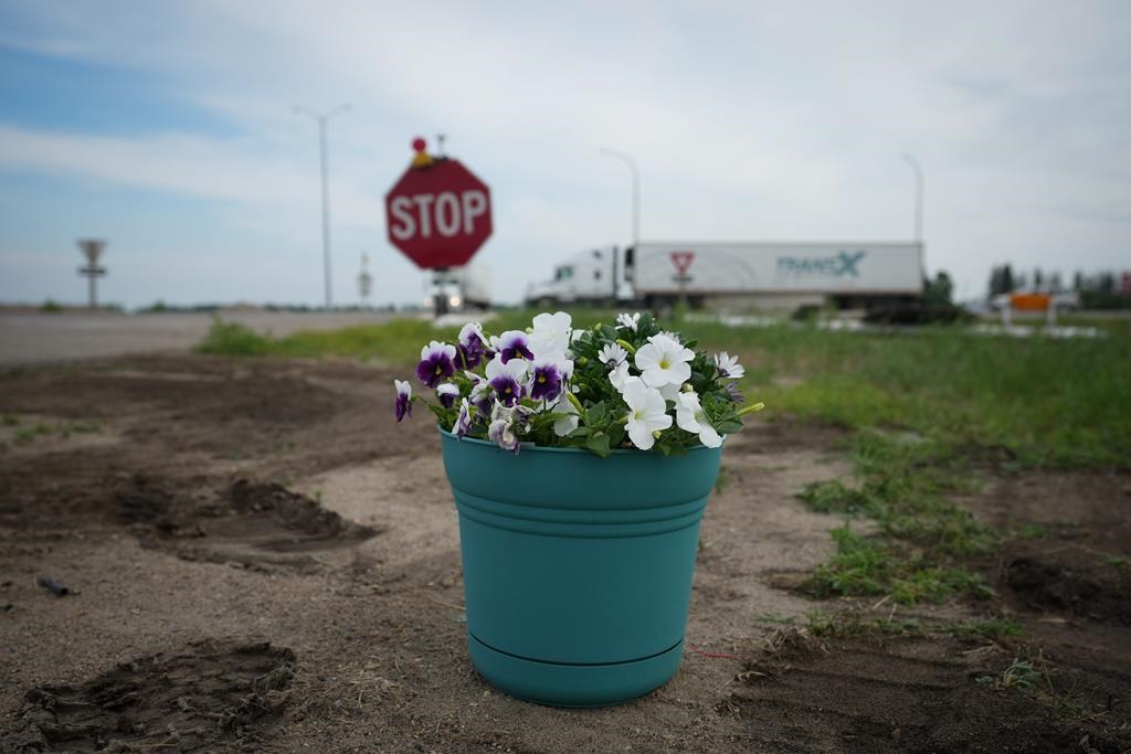 Flowers that were left by a person are seen on the side of the road where the Trans-Canada Highway intersects with Highway 5, west of Winnipeg near Carberry, Man., Friday, June 16, 2023, where a semi and a bus carrying seniors collided on June 15. RCMP say another person involved in the crash succumbed to their injuries. THE CANADIAN PRESS/Darryl Dyck.