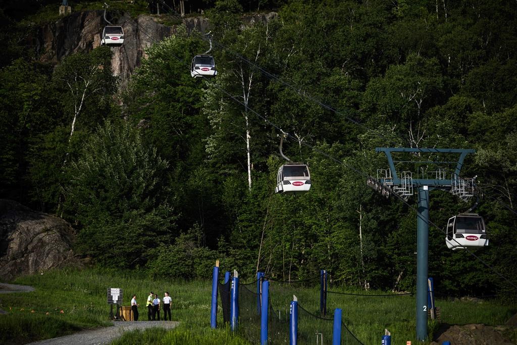 Cadets from the Sûreté du Québec stand near the base of a chairlift where one person died and another remains critically injured after a gondola crashed into a piece of construction equipment at Mont-Tremblant Resort in Mont-Tremblant, Que., on Sunday, July 16, 2023.