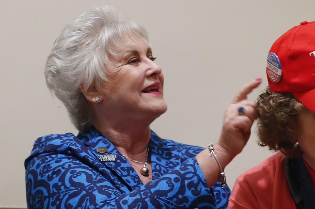 FILE – Kathy Berden looks at buttons on a hat during a training session for Women for Trump, An Evening to Empower, Thursday, Aug. 22, 2019, in Troy, Mich. (AP Photo/Paul Sancya, File)