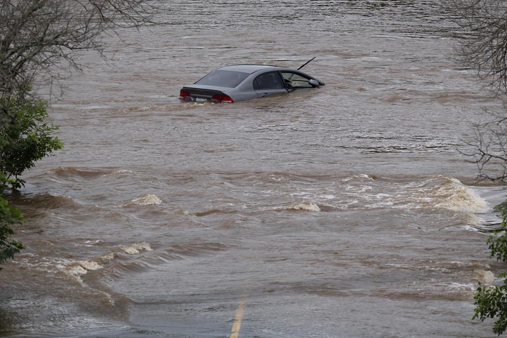 An abandoned car in a mall parking lot is seen in floodwater following a major rain event in Halifax on Saturday, July 22, 2023. Searchers are continuing to pump water from a flooded field in Nova Scotia that is the focus of an extensive search for four people, including two children, who went missing in a torrent of water Saturday. THE CANADIAN PRESS/Darren Calabrese