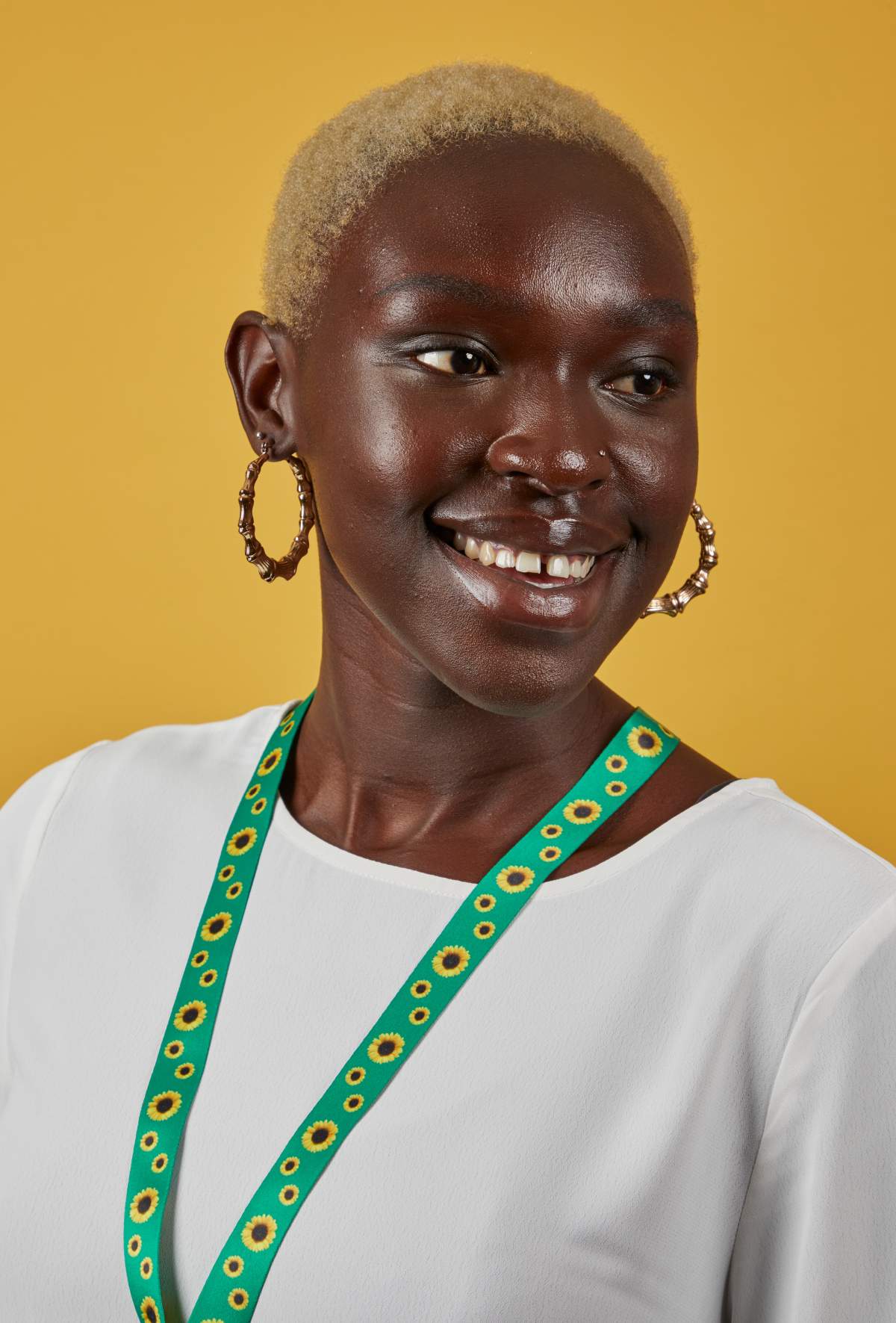 A photo of a women smiling while wearing the sunflower lanyard.