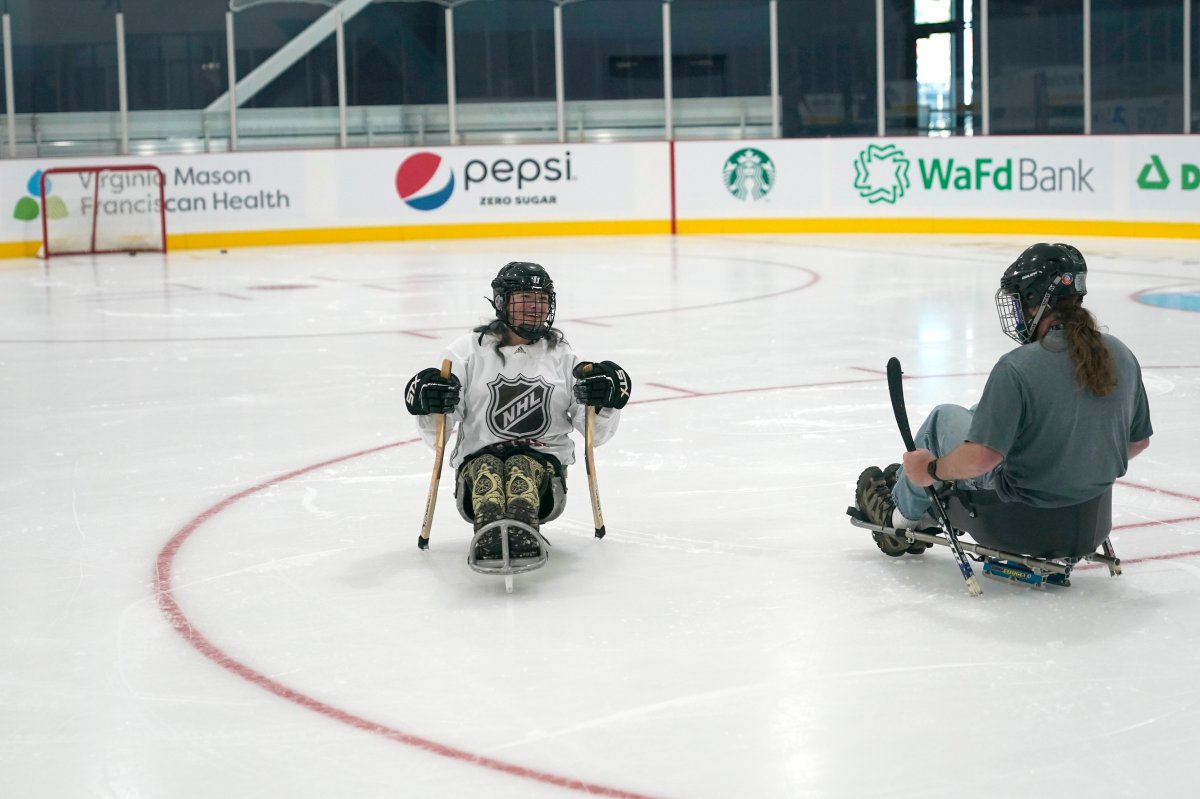 Two people sit on the ice before playing sled hockey, a sport accessible to players with physical disabilities, Thursday, Sept. 9, 2021, during a media event for the opening of the Seattle Kraken's NHL hockey practice and community facility in Seattle. In addition to being the Kraken's practice headquarters, the facility's three sheets of ice will be used for community teams and other activities.