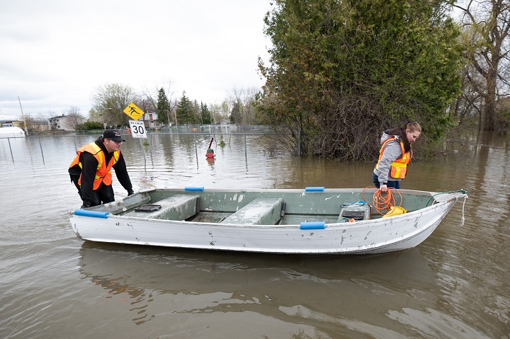 Kévin Masson, left, and Mélody Bastien, local residents of Cantley, Que. make their way to dry land after searching and assisting in the evacuation of local residents  on Thursday, May 4, 2023. Flood warnings are in effect for the national capital region following significant rainfall and increased water runoff. 