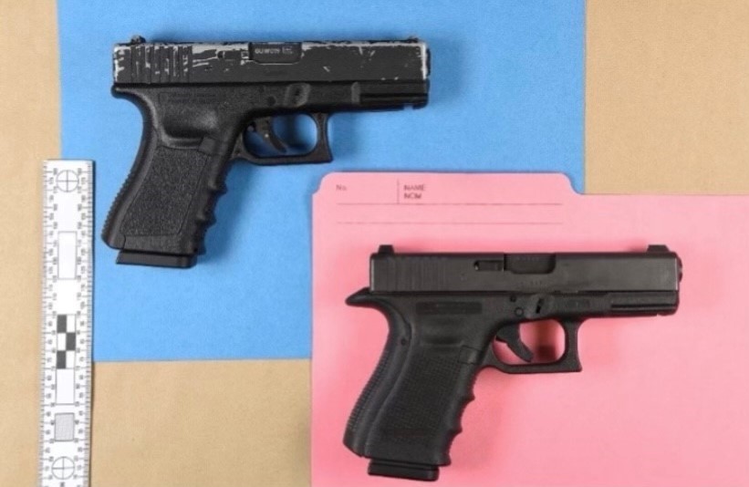 The gun in the blue background is a replica. The one in the pink background is real.