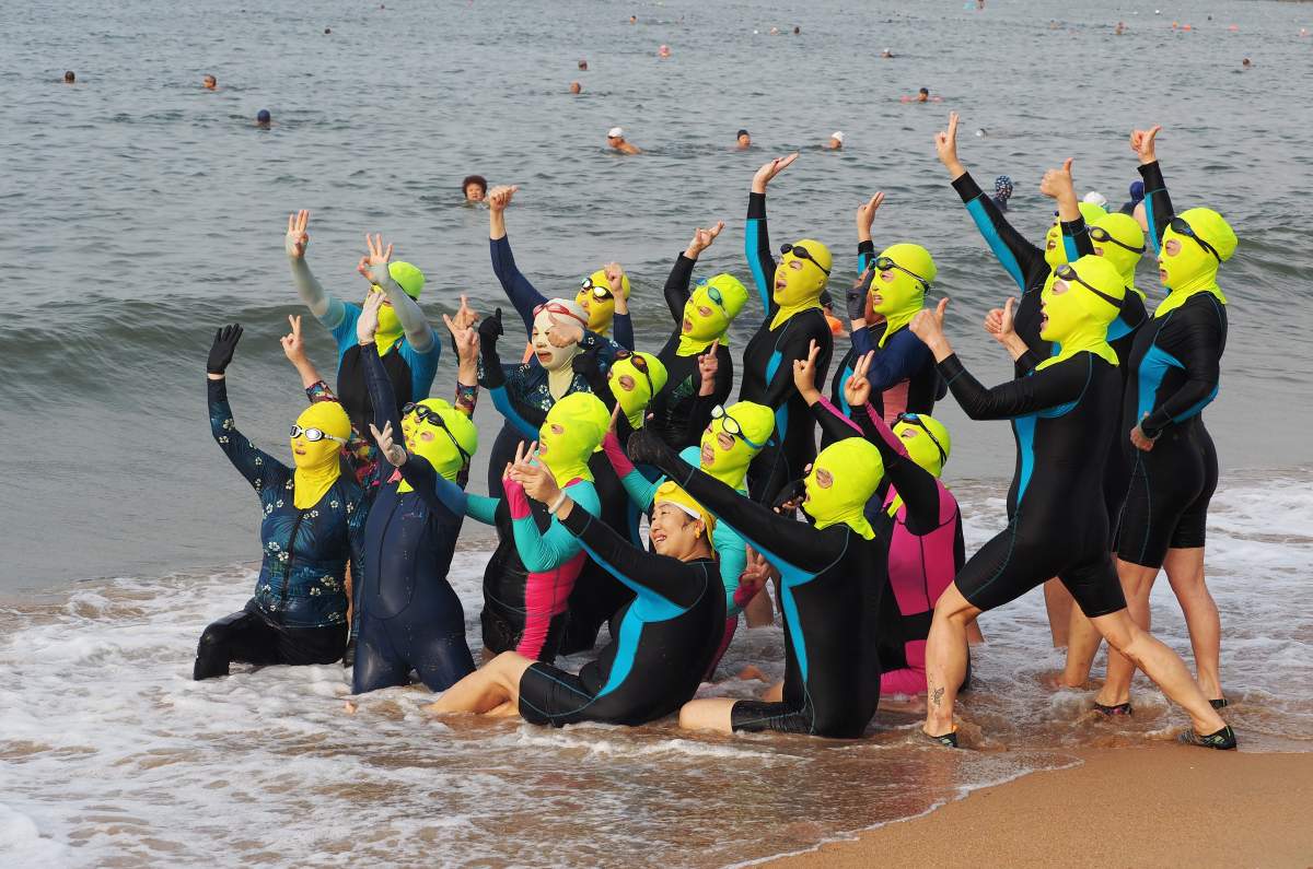 A team of female swimmers wearing facekini pose on beach by the sea on August 18, 2020 in Qingdao, Shandong Province of China.