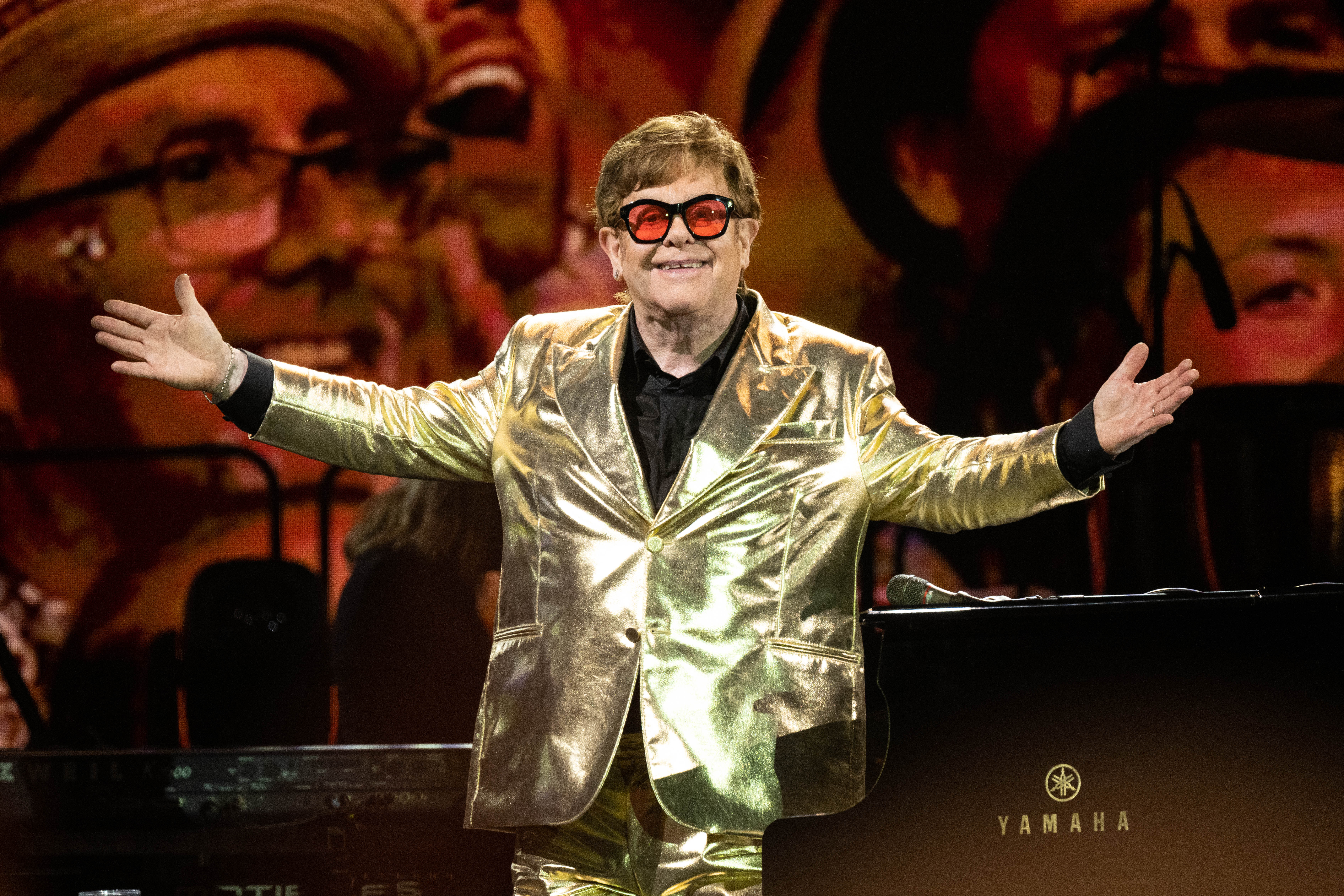 Elton John on stage in a gold suit.