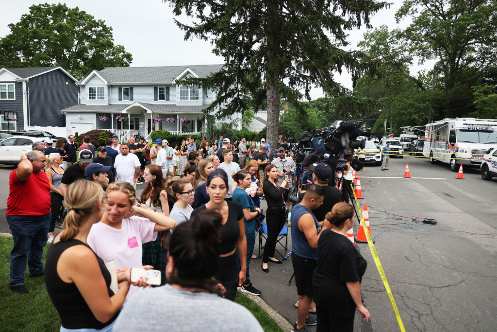People watch as law enforcement officials investigate the home of a suspect arrested in the unsolved Gilgo Beach killings on July 14, 2023 in Massapequa Park, New York.
