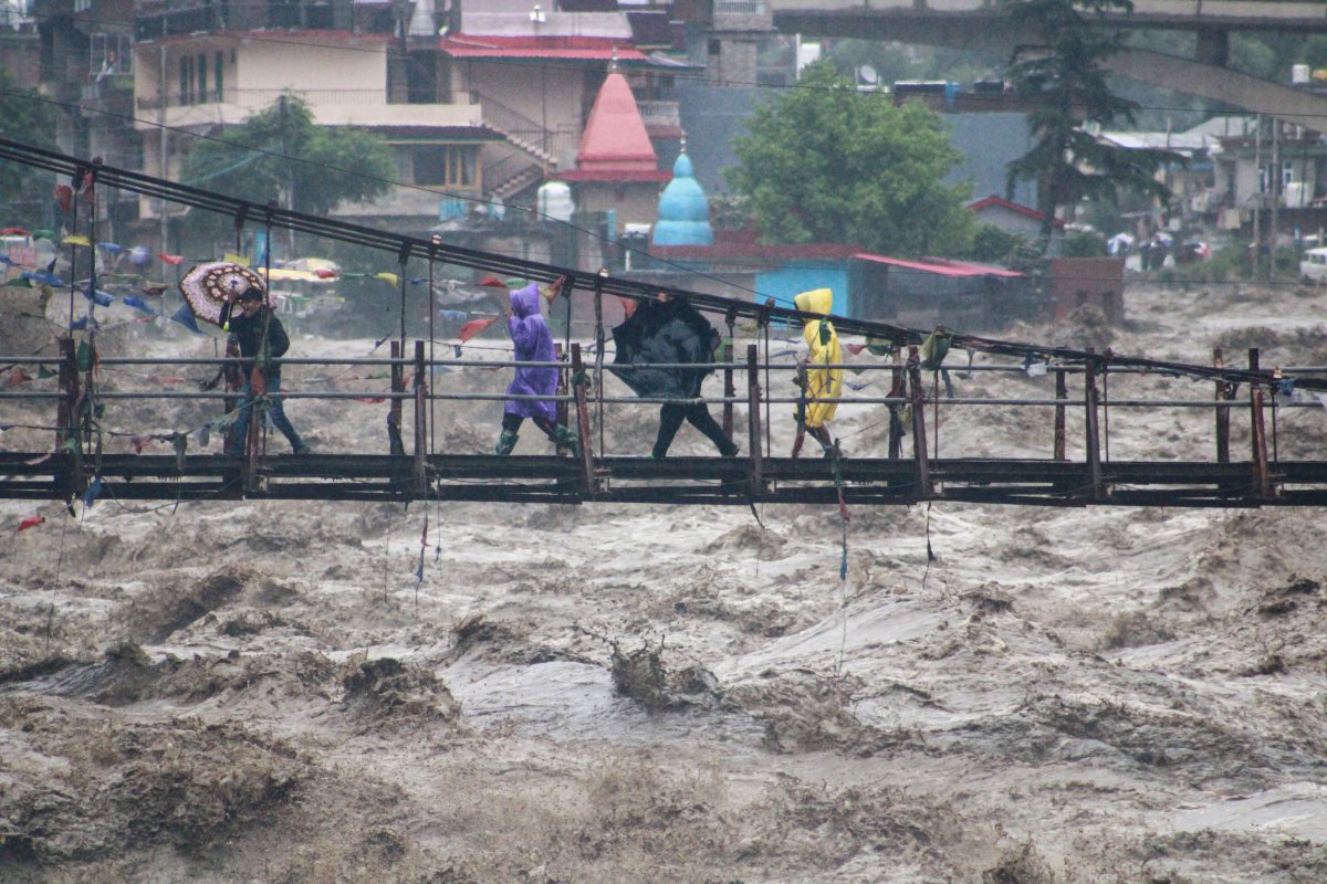 People walk through a bridge across River Beas swollen due to heavy rains in Kullu District, Himachal Pradesh, India, Monday, July 10, 2023. Scientists have long warned that more extreme rainfall is expected in a warming world. (AP Photo/Aqil Khan)