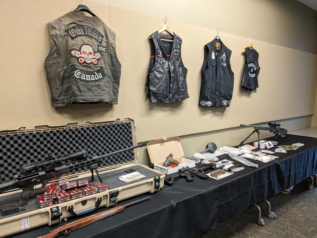 A table filled with various evidence, including firearms, drugs, and vests.