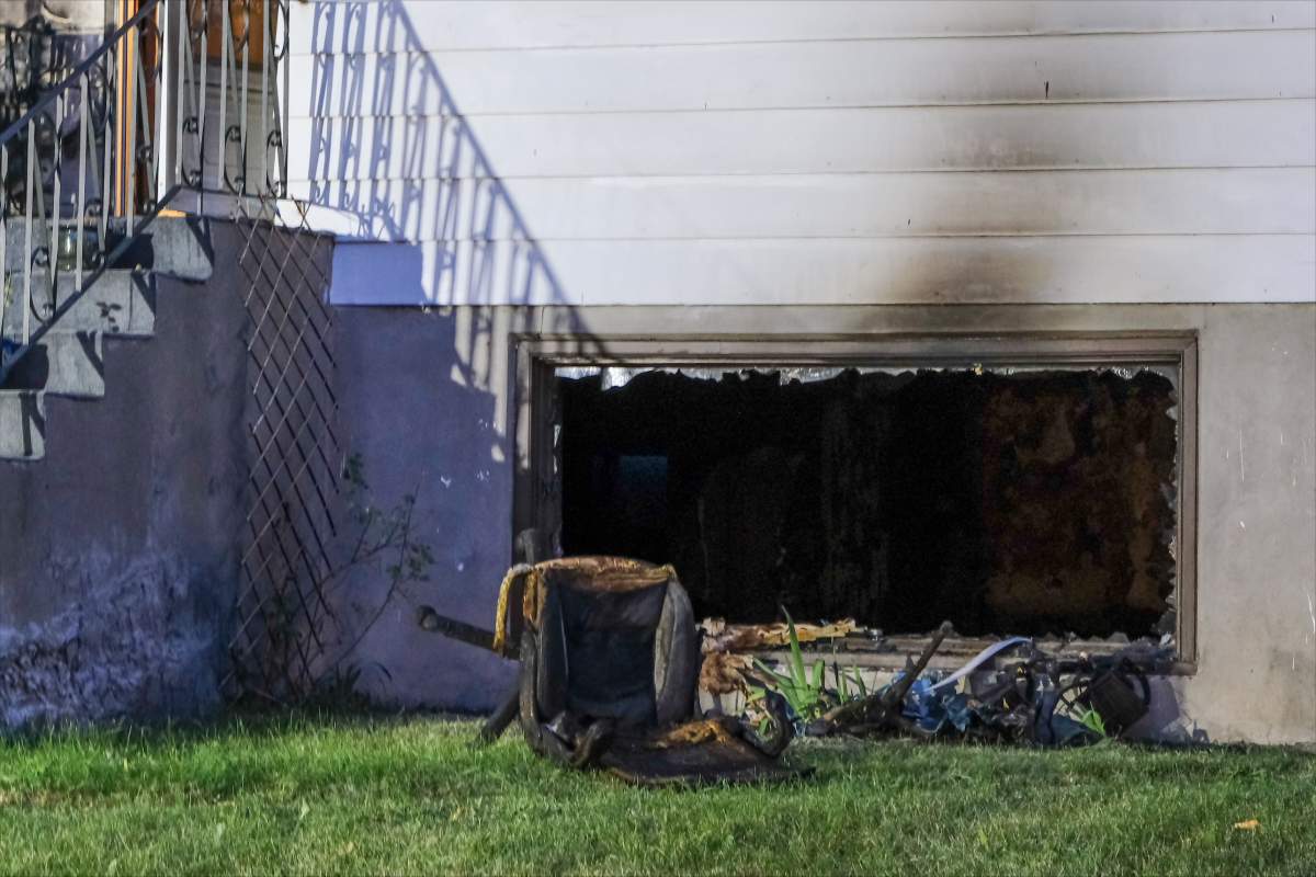 A broken basement window and fire damage seen after a house fire killed two people at a Calgary residence on July 26, 2023.