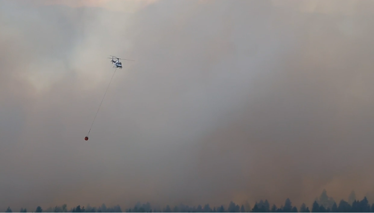 A helicopter carries water towards the St. Mary's River wildfire near Cranbrook. 