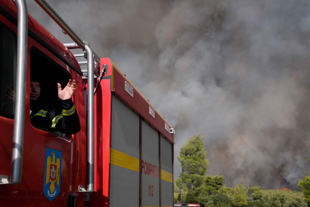 A firefighter from Romania in a firefighting truck, gives instructions during a fire at the village of Agia Sotira near Athens, on Tuesday, July 18, 2023. In Greece, where a second heatwave is expected to hit Thursday, three large wildfires burned outside Athens for a second day. Thousands of people evacuated from coastal areas south of the capital returned to their homes Tuesday when a fire finally receded after they spent the night on beaches, hotels and public facilities. (AP Photo/Thanassis Stavrakis)