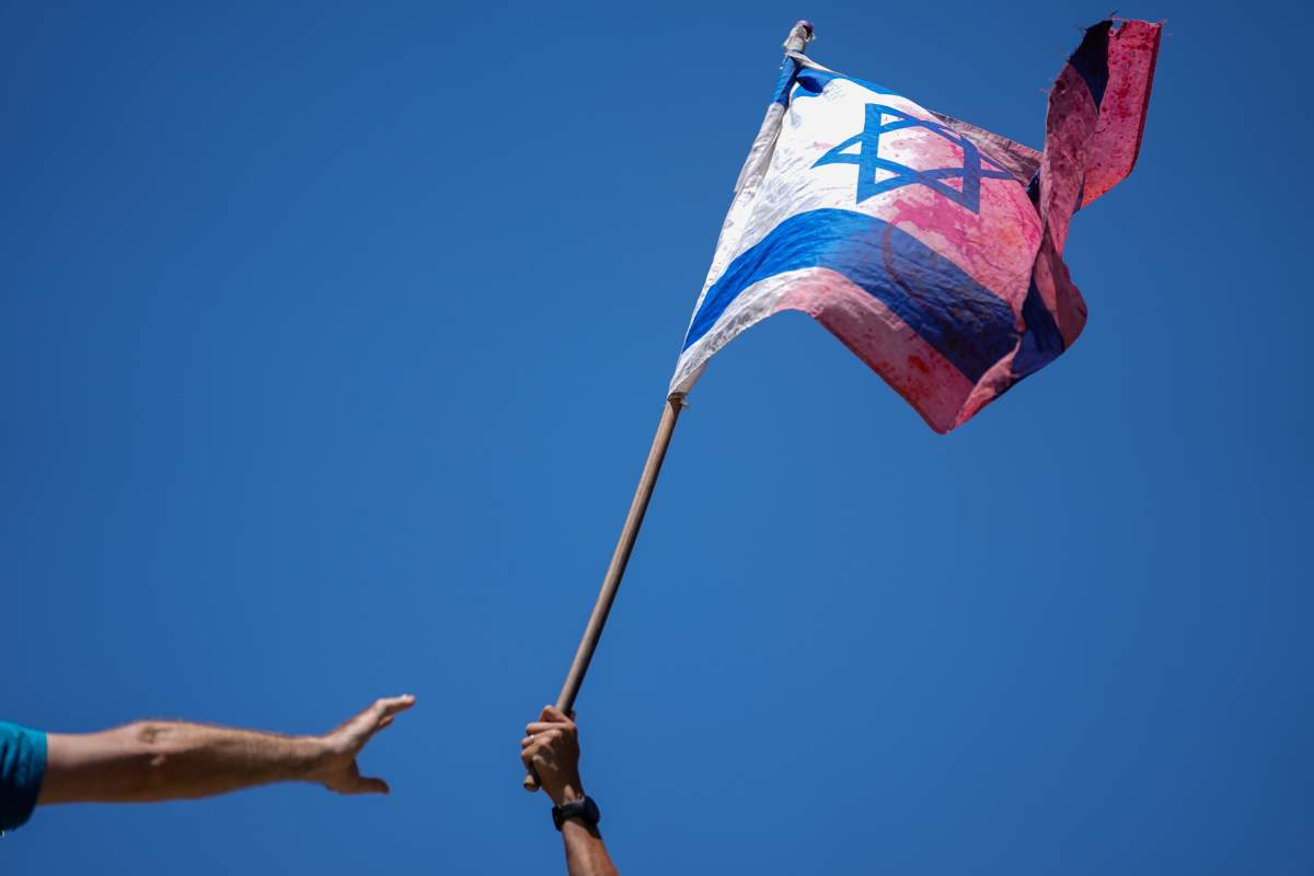 A demonstrator waves a colored Israeli flag during a protest against plans by Prime Minister Benjamin Netanyahu’s government to overhaul the judicial system, outside the Knesset, Israel’s parliament, in Jerusalem, Monday, July 24, 2023. The demonstration came hours before parliament was set to vote on a key part of the plan. (AP Photo/Ariel Schalit)