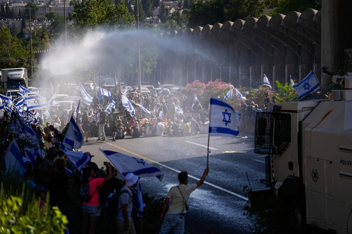 Israeli police use a water cannon to disperse demonstrators blocking a road during a protest against plans by Prime Minister Benjamin Netanyahu’s government to overhaul the judicial system, in Jerusalem, Monday, July 24, 2023. (AP Photo/Ariel Schalit)