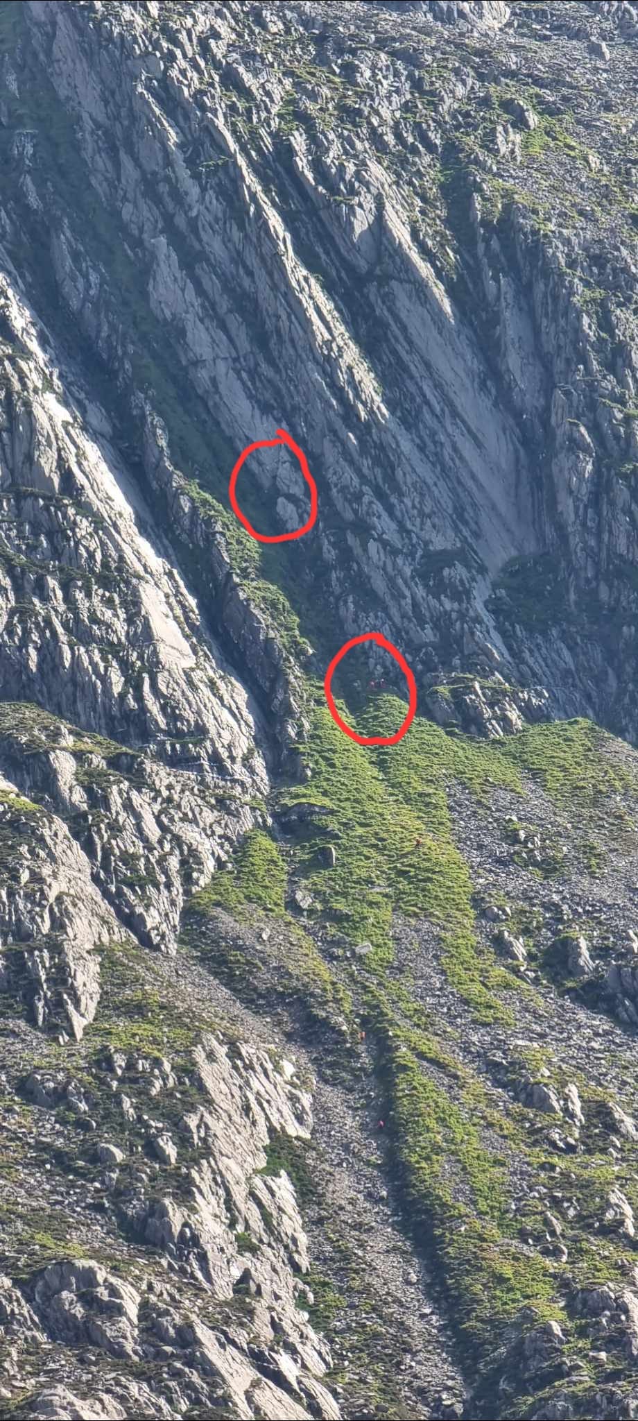 Location of the woman stuck on a cliff (top bubble) and the rescuers below her trying to reach her location.