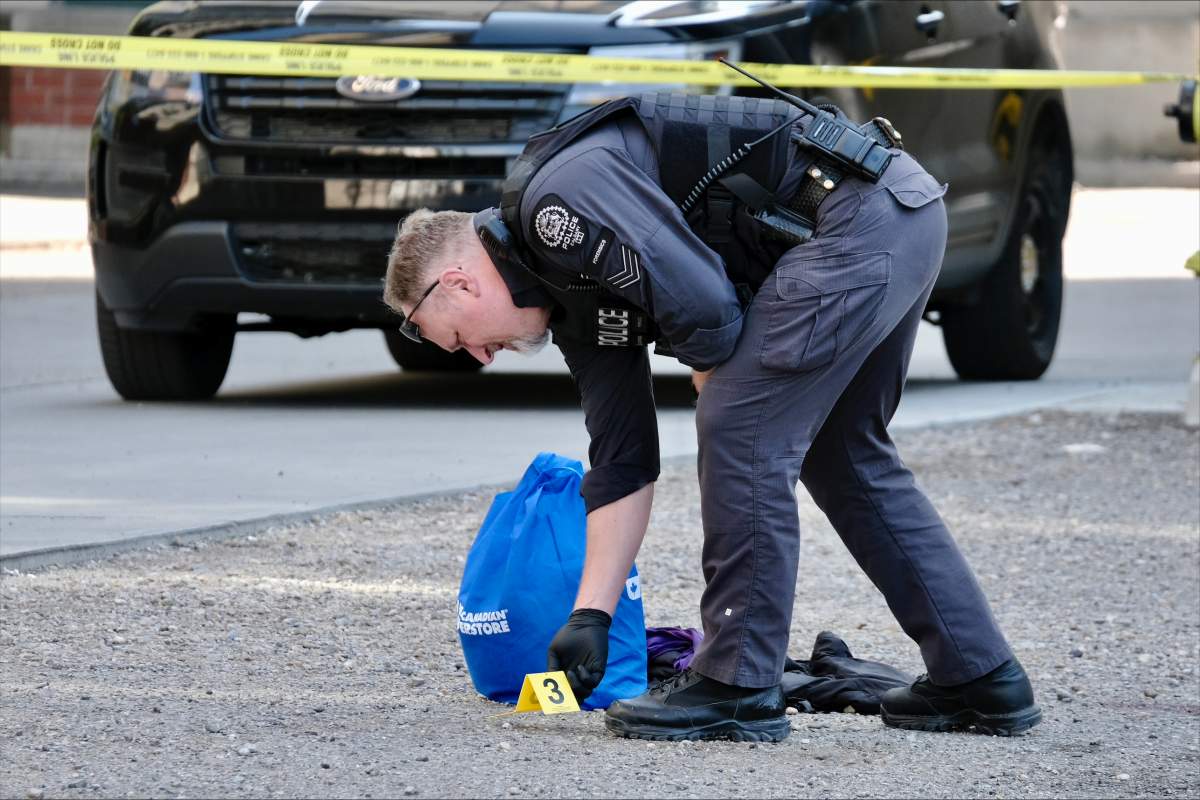 A Calgary Police Service member places an evidence marker in a parking lot in the 1100 block of Seventh Avenue Southwest during a shooting investigation on July 10.