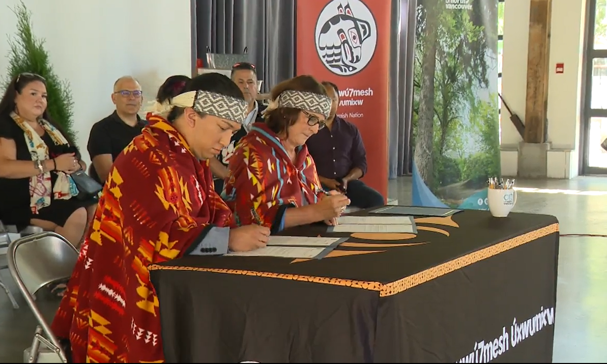 Sḵwx̱wú7mesh Úxwumixw Council Chairperson Khelsilem signs a protocol agreement with North Vancouver Mayor Linda Buchanan on Sat. July 15, 2023.