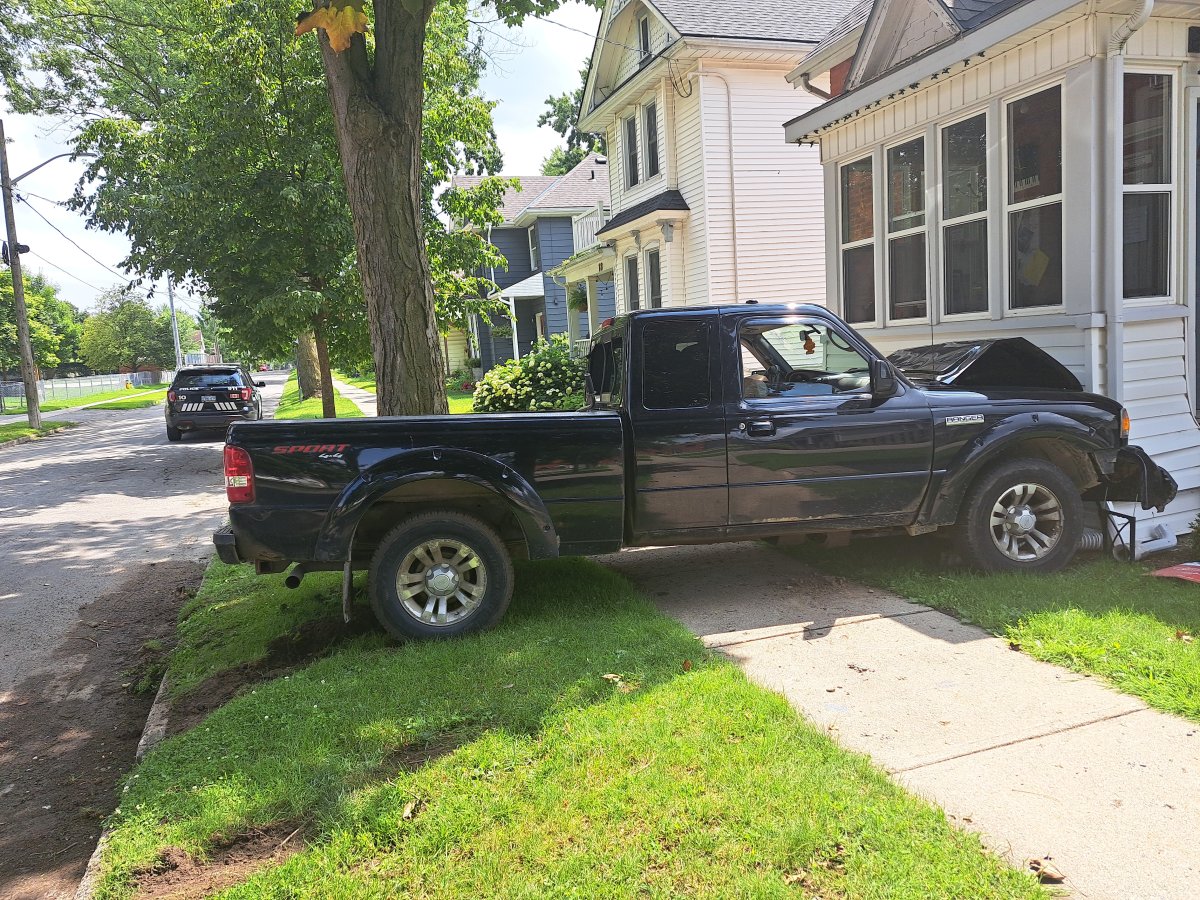 A black pickup collided with a white house on a summer afternoon.