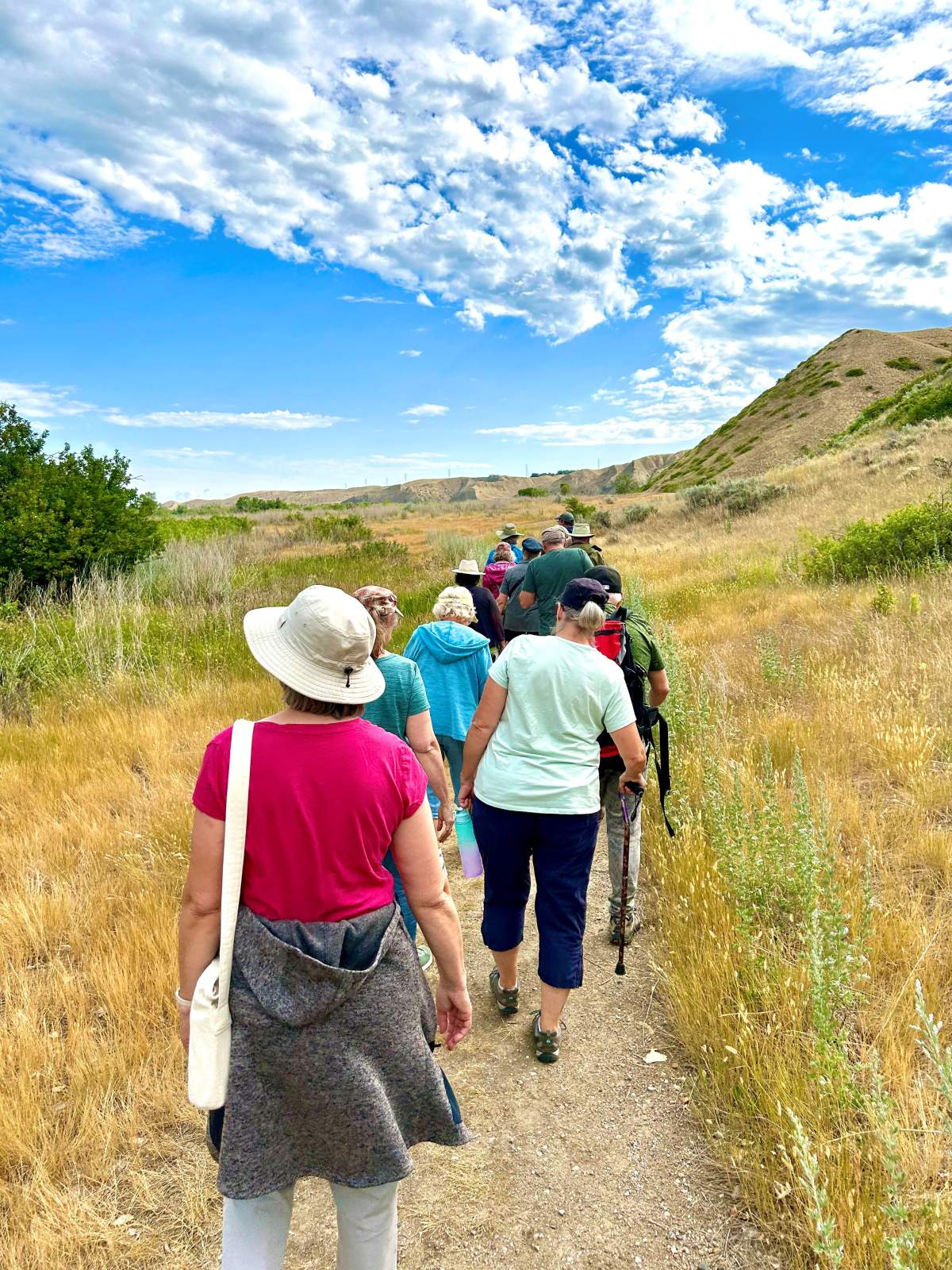 People walking on a small dirt path in the Lethbridge River Bottom.