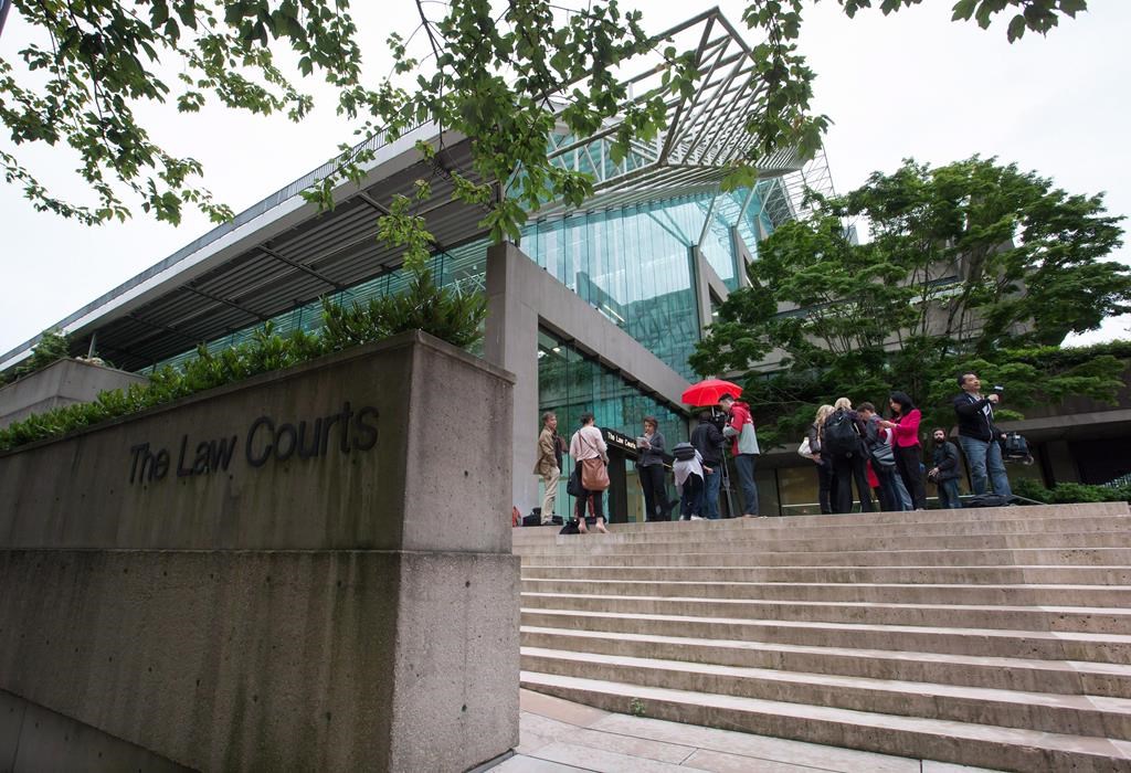 Media wait outside court in Vancouver, on June 2, 2015. The B.C. Court of Appeal has struck down a six-month prison sentence for a trans youth's father who was convicted of contempt for publicly discussing his child's private medical details in breach of a court order. THE CANADIAN PRESS/Darryl Dyck.