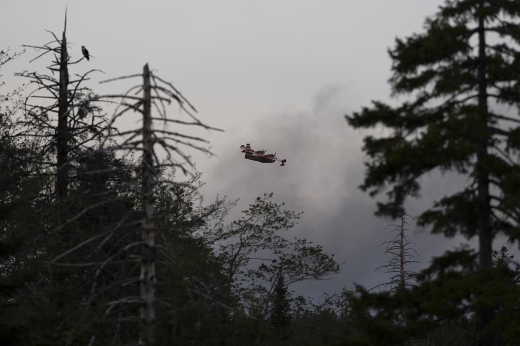 A water bomber flies through heavy smoke as an out-of-control wildfire in a suburban community outside Halifax quickly spread, engulfing multiple homes and forcing the evacuation of local residents on Sunday May 28, 2023.