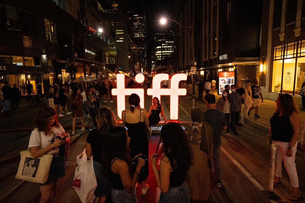 Visitors to the Toronto International Film Festival take photos in front of a TIFF sign in Toronto on Friday, September 9, 2022.
