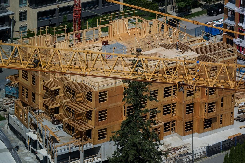 A construction worker is seen on top of a low-rise condo development being built in Coquitlam, B.C., on Tuesday, May 16, 2023.