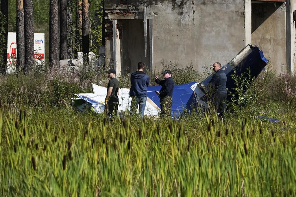 Russian servicemen inspect a part of a crashed private jet near the village of Kuzhenkino, Tver region, Russia, Thursday, Aug. 24, 2023. Russian mercenary leader Yevgeny Prigozhin, the founder of the Wagner Group, reportedly died when a private jet he was said to be on crashed on Aug. 23, 2023, killing all 10 people on board. (AP Photo/Alexander Zemlianichenko).