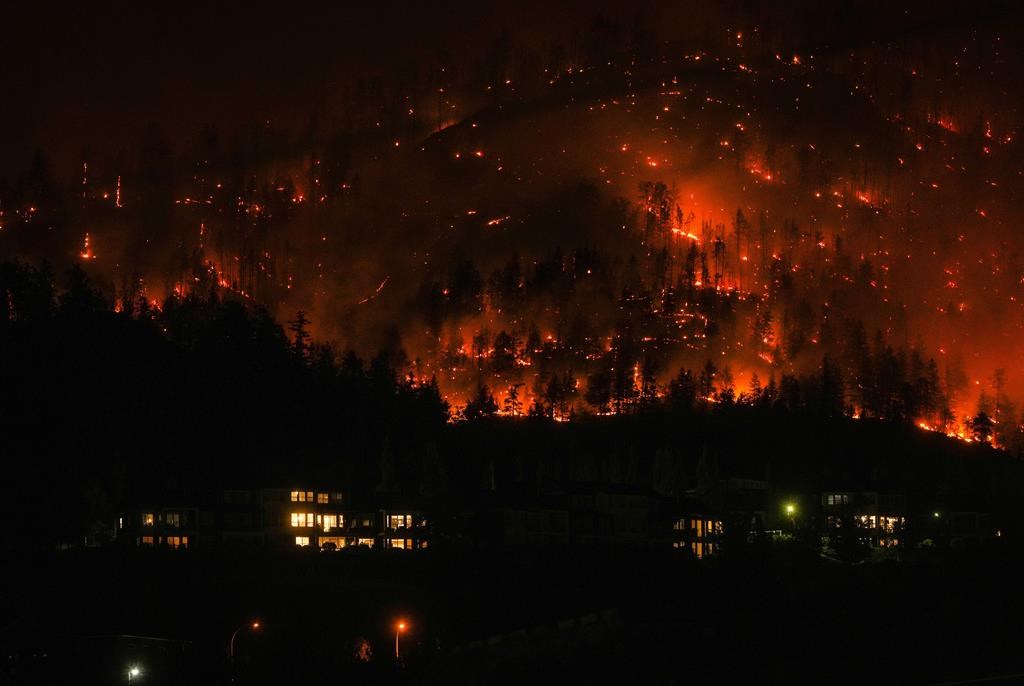 The McDougall Creek wildfire burns on the mountainside above houses in West Kelowna, B.C., on Friday, August 18, 2023.