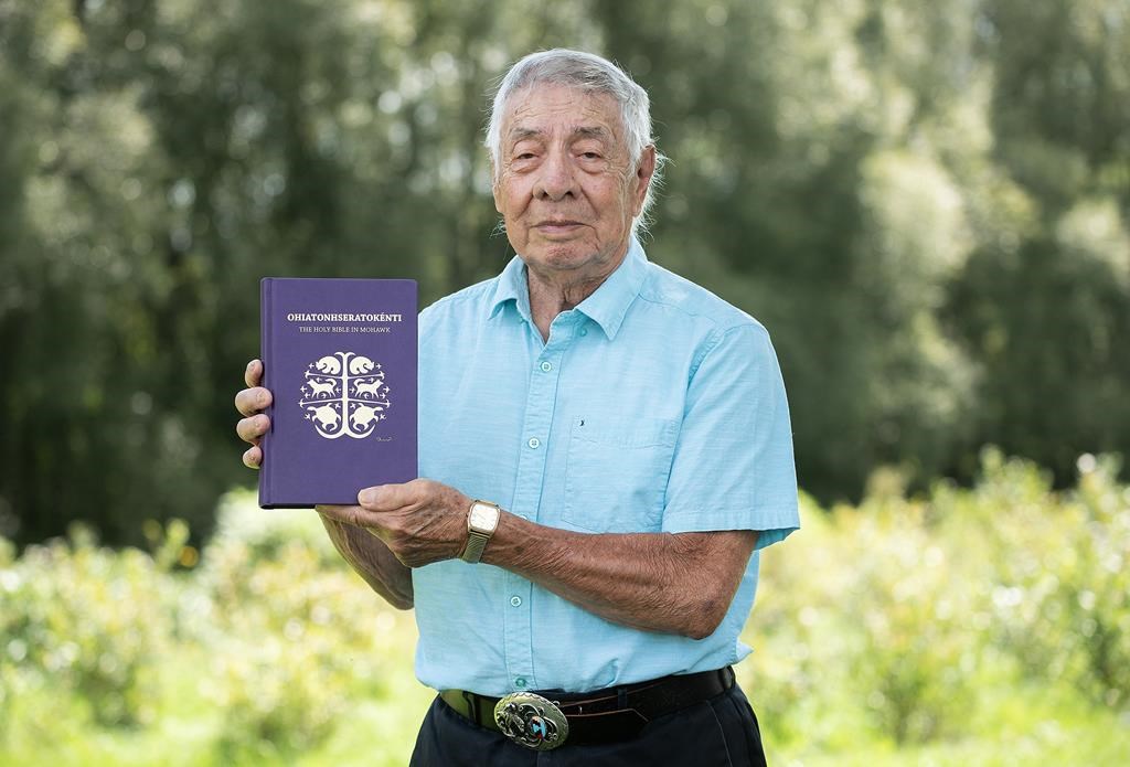 Harvey Satewas Gabriel poses with a copy of the Bible which he translated from English into Mohawk at his home in Kanesatake, Que., Sunday, Aug. 27, 2023. THE CANADIAN PRESS/Graham Hughes.
