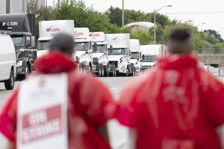 Trucks waiting to enter Metro warehouse facilities are seen as striking employees of the grocery store Metro stand on the picket lines in Toronto, on Wednesday, Aug. 23, 2023. 