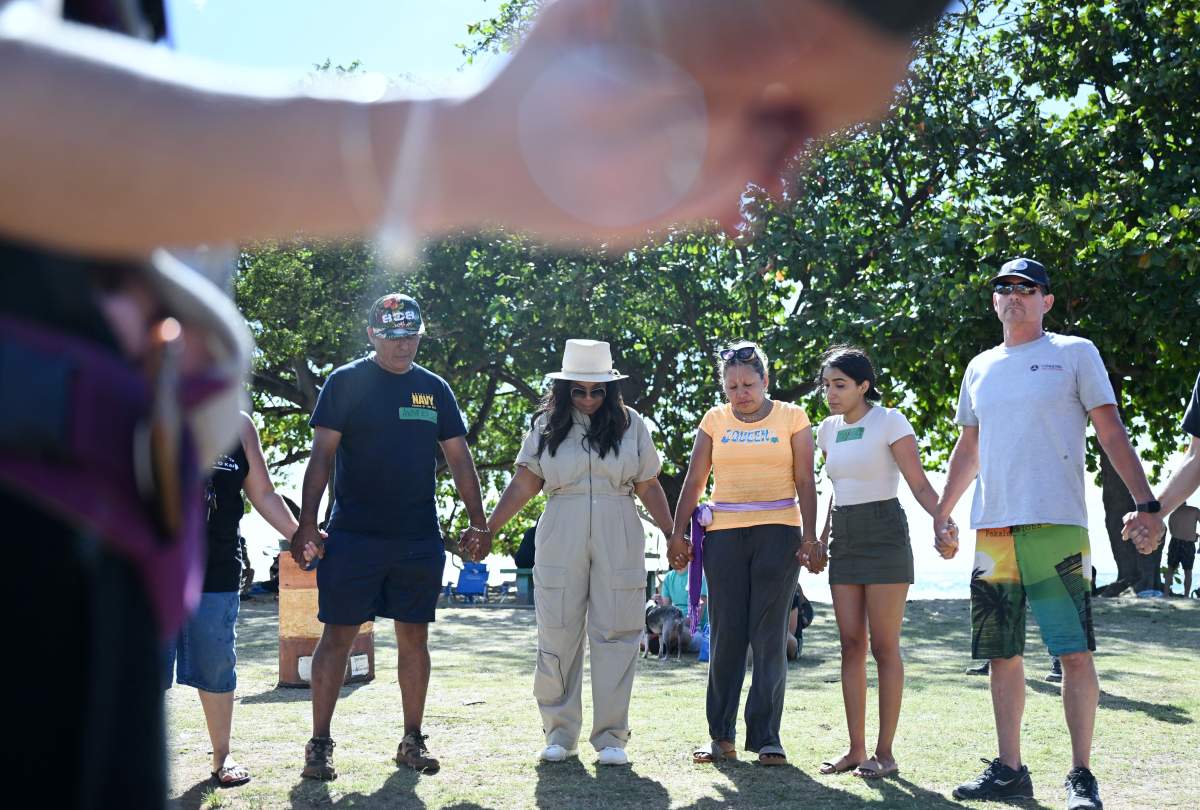 Andres Garcia, left center, holds hands with Oprah Winfrey, center, and Luz Vargas, right, at a distribution and aid site at Honokowai Beach Park on Sunday August 13, 2023 in Honokowai, HI.