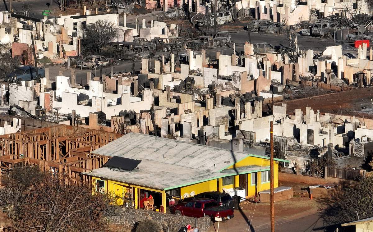 A yellow home stands alone amid rubble and ash.