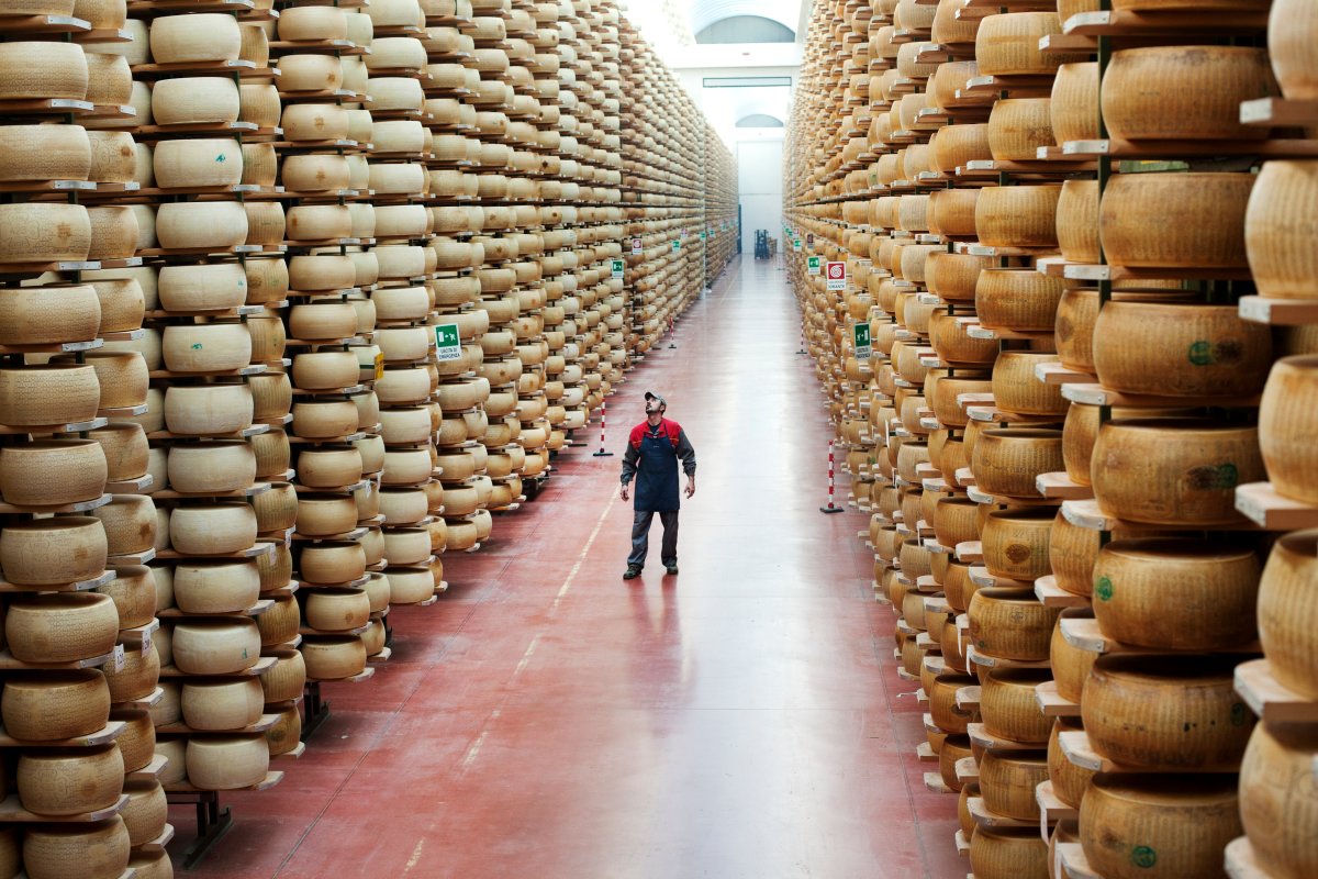 File - Man at work in a warehouse full of aging Parmesan and Grana Padano cheese wheels on January 01, 2012.
