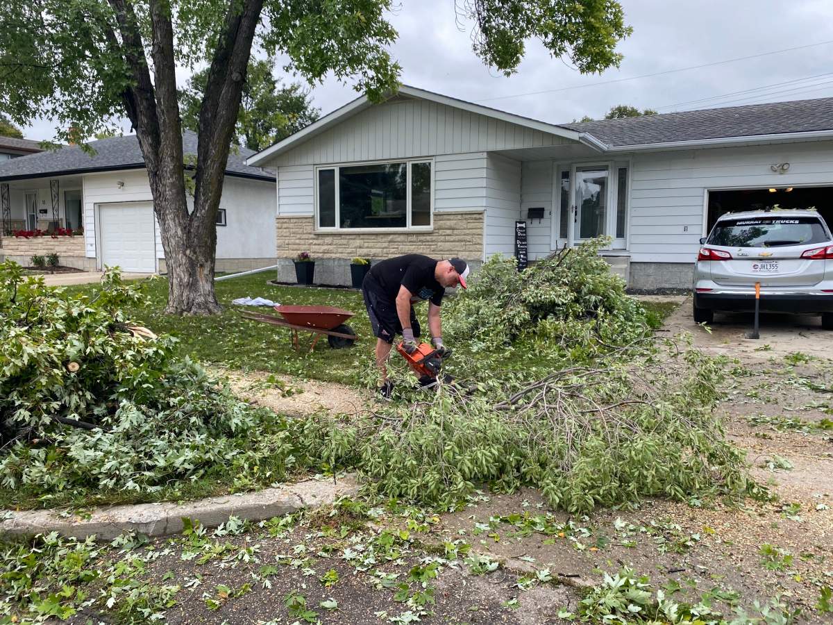 Winnipeg resident Chris Kerr cleans up debris after Thursday’s storm.