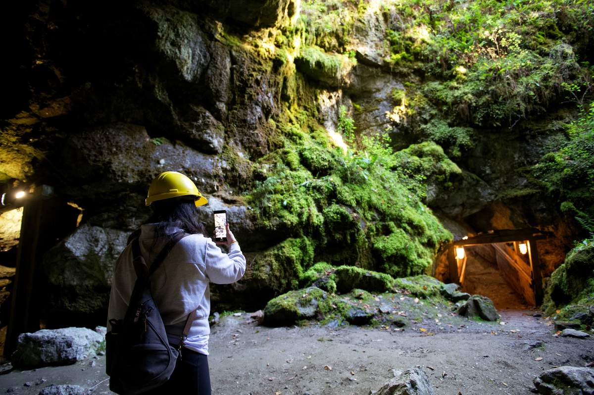 A woman taking a photo of the entrance to a mine.