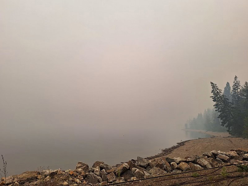 Wildfire smoke covers Adams Lake in this photo. Two large fires are burning on opposite sides of the lake. 