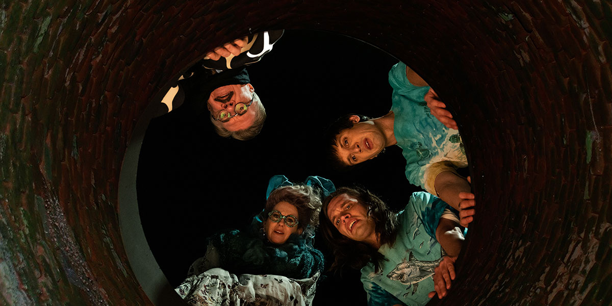 A still from 'Dicks: The Musical.' Four actors stare down into a hole.